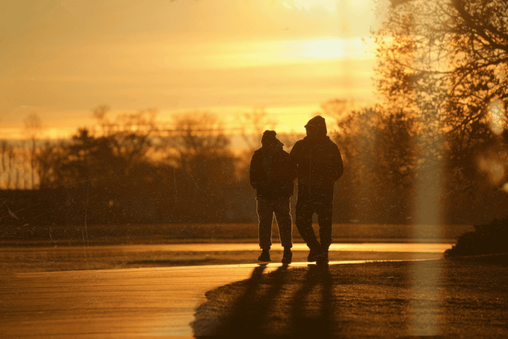 Two people walking and talking together, silhouetted against a golden sunset