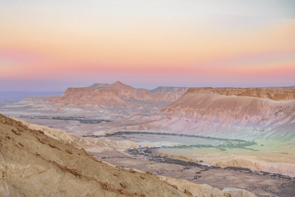 A desert canyon landscape glowing under a soft pink dawn sky